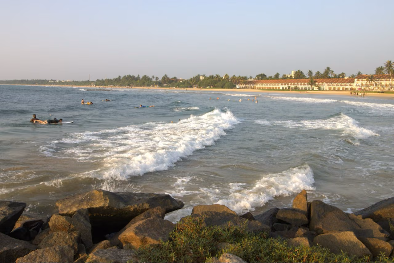 Bentota golden sand beach with turquoise waves and tropical palm trees in southern Sri Lanka